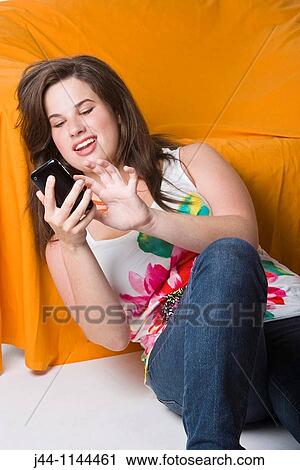 Young woman using mobile phone leaning on sofa smiling View Large Photo Image Stock Image - Young woman using mobile phone leaning on sofa smiling. Fotosearch