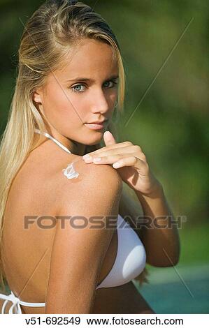 Young woman using sunblock by a pool View Large Photo Image Stock Photo - Young woman using sunblock by a pool. Fotosearch