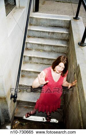Stock Photography - Young woman walking down a set of concrete stairs.. Fotosearch