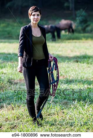 Young woman walking in a pasture with horses in the background View Large Photo Image Stock Photograph - Young woman walking in a pasture with horses in the background. Fotosearch
