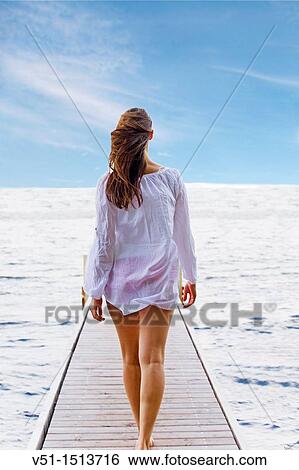 Stock Photograph - Young woman walking untill the end of a pier. Fotosearch
