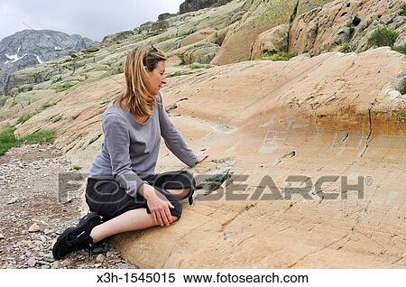 Stock Photography - young woman watching the petroglyph named Le Sorcier Vallee des Merveilles, Mercantour National Park Alpes-Maritimes department, Provence-Alpes-Cote d? Azur region, southeast of France, Europe. Fotosearch