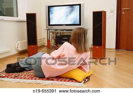 Stock Image - Young woman watching TV. Fotosearch