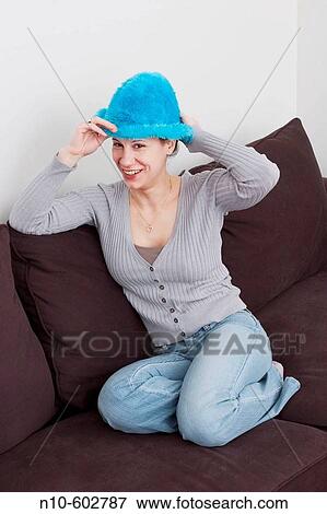 Young woman, wearing a blue hat, sitting on a sofa. View Large Photo Image Stock Photo - Young woman, wearing a blue hat, sitting on a sofa.. Fotosearch