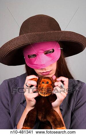 Young woman, wearing a hat and pink mask, holding a stuffed animal View Large Photo Image Stock Image - Young woman, wearing a hat and pink mask, holding a stuffed animal. Fotosearch
