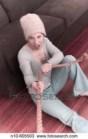 Young woman, wearing a hat and sitting on the floor, pulling on a rope. View Large Photo Image Stock Image - Young woman, wearing a hat and sitting on the floor, pulling on a rope.. Fotosearch