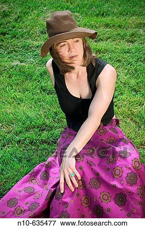 Young woman, wearing a hat, posing on the grass at a park View Large Photo Image Stock Photo - Young woman, wearing a hat, posing on the grass at a park. Fotosearch