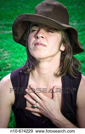 Young woman, wearing a hat, posing on the grass at a park. View Large Photo Image Stock Photo - Young woman, wearing a hat, posing on the grass at a park.. Fotosearch