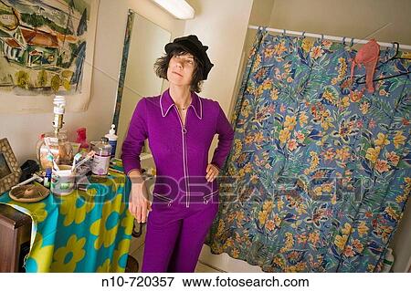Stock Photo - Young woman, wearing a hat, standing in her bathroom.. Fotosearch