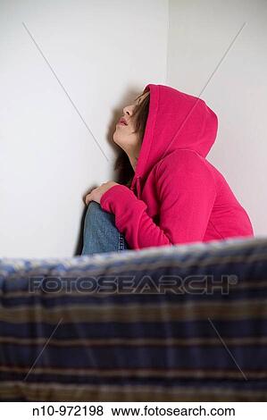 Young woman, wearing a hooded sweatshirt, sitting on her bed View Large Photo Image Stock Photo - Young woman, wearing a hooded sweatshirt, sitting on her bed. Fotosearch