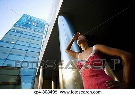 Young woman wearing a pink dress shields her eyes as she looks up at surrounding buildings. Boston, Massachusetts, USA View Large Photo Image Stock Photography - Young woman wearing a pink dress shields her eyes as she looks up at surrounding buildings. Boston, Massachusetts, USA. Fotosearch