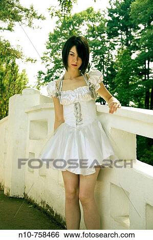 Stock Photograph - Young woman, wearing a white dress, standing on a bridge.. Fotosearch