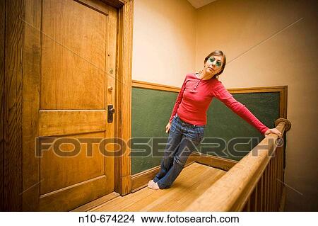 Young woman, wearing blue sunglasses, posing in the hallway of her apartment building. View Large Photo Image Picture - Young woman, wearing blue sunglasses, posing in the hallway of her apartment building.. Fotosearch