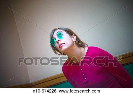 Young woman, wearing blue sunglasses, posing in the hallway of her apartment building. View Large Photo Image Stock Photograph - Young woman, wearing blue sunglasses, posing in the hallway of her apartment building.. Fotosearch