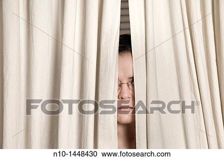 Young woman, wearing glasses, peeking out from behind two curtains View Large Photo Image Stock Image - Young woman, wearing glasses, peeking out from behind two curtains. Fotosearch
