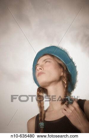 Stock Image - Young woman, wearing pigtails and a hat, posing. Fotosearch