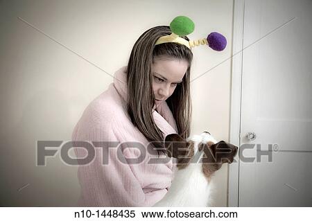 Stock Photography - Young woman, wearing pom-poms on her head, with her dog. Fotosearch