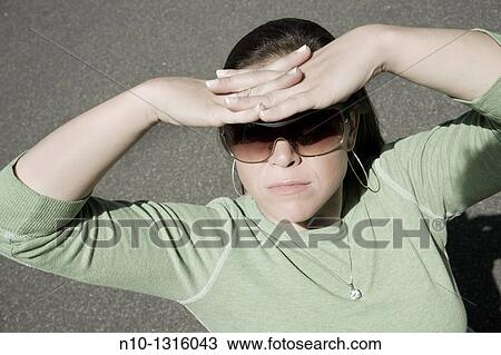 Young woman, wearing sunglasses, blocking the sun with her hands View Large Photo Image Stock Image - Young woman, wearing sunglasses, blocking the sun with her hands. Fotosearch