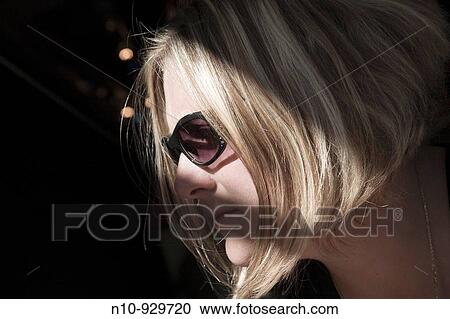 Stock Image - Young woman wearing sunglasses. Fotosearch