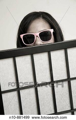 Stock Photo - Young woman, wearing sunglasses, looking over the top of a screen.. Fotosearch