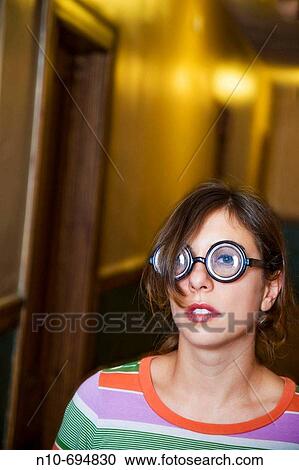 Young woman, wearing thick glasses, posing in the hallway of her apartment building View Large Photo Image Stock Image - Young woman, wearing thick glasses, posing in the hallway of her apartment building. Fotosearch