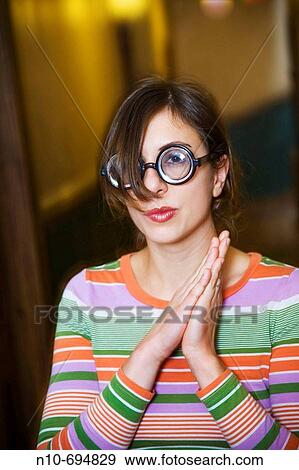 Stock Photo - Young woman, wearing thick glasses, posing in the hallway of her apartment building. Fotosearch