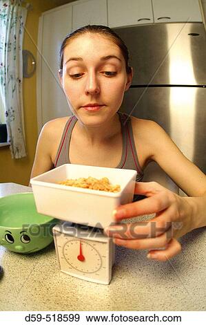 Young woman weighing food on a diet scale View Large Photo Image Stock Photo - Young woman weighing food on a diet scale. Fotosearch
