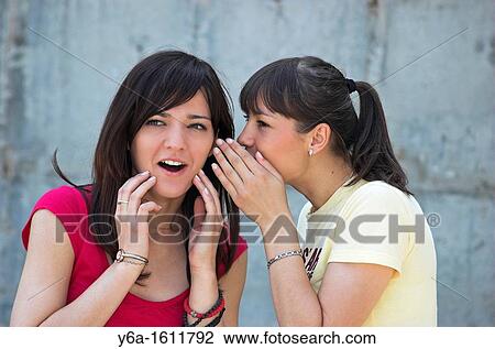 Young woman whispering to her friend View Large Photo Image Stock Image - Young woman whispering to her friend. Fotosearch