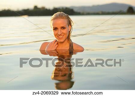 Stock Photo - Young woman with a bikini bathing in a lake in Austria. Fotosearch