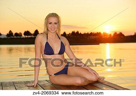 Young woman with a bikini on a jetty at a lake in Austria by sunset View Large Photo Image Picture - Young woman with a bikini on a jetty at a lake in Austria by sunset. Fotosearch