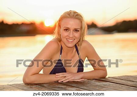 Young woman with a bikini on a jetty at a lake in Austria by sunset View Large Photo Image Stock Photography - Young woman with a bikini on a jetty at a lake in Austria by sunset. Fotosearch