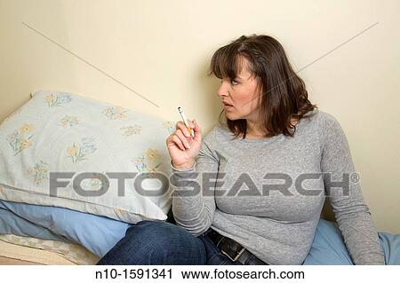 Young woman, with a cigarette, sitting on her bed View Large Photo Image Stock Image - Young woman, with a cigarette, sitting on her bed. Fotosearch