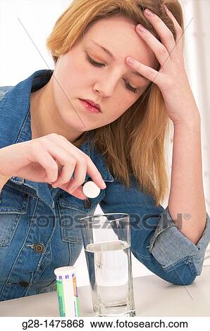 Stock Photo - young woman with a headache taking an aspirin tablet. Fotosearch