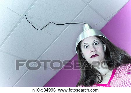 Young woman with a metal hood, which is attached to a wire dropping down from the ceiling, setting on her head. View Large Photo Image Stock Image - Young woman with a metal hood, which is attached to a wire dropping down from the ceiling, setting on her head.. Fotosearch