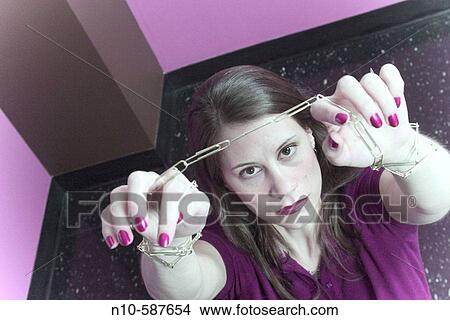 Young woman with a paper clip chain binding her wrists. View Large Photo Image Picture - Young woman with a paper clip chain binding her wrists.. Fotosearch