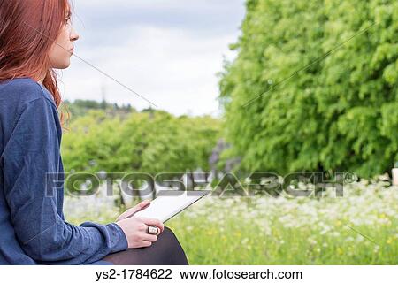 Young woman with a tablet pc in her lap, looking at the nature View Large Photo Image Stock Image - Young woman with a tablet pc in her lap, looking at the nature. Fotosearch