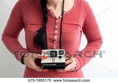 Stock Image - young woman with an old Polaroid camera. Fotosearch