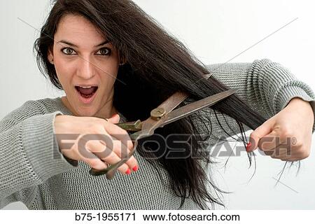 Stock Image - young woman with astonished face making herself a haircut. Fotosearch