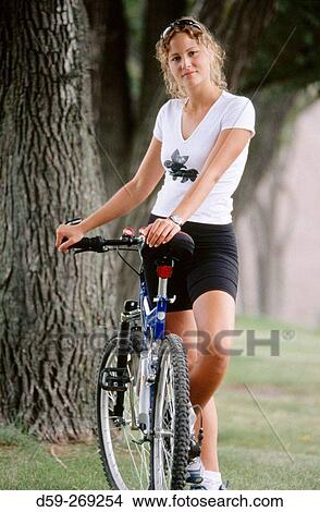 Picture - Young woman with bike, looking at camera. Fotosearch