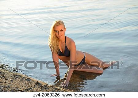 Young woman with bikini lying at the shore of a lake in Austria. View Large Photo Image Stock Photograph - Young woman with bikini lying at the shore of a lake in Austria.. Fotosearch