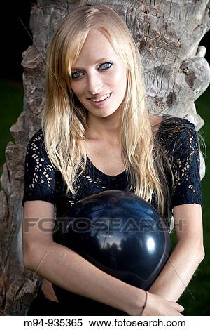 Stock Photography - Young woman with black balloon looking at camera. Fotosearch