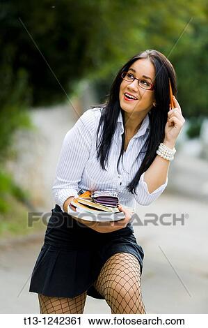 Young woman with books in hand is laughing View Large Photo Image Stock Image - Young woman with books in hand is laughing. Fotosearch