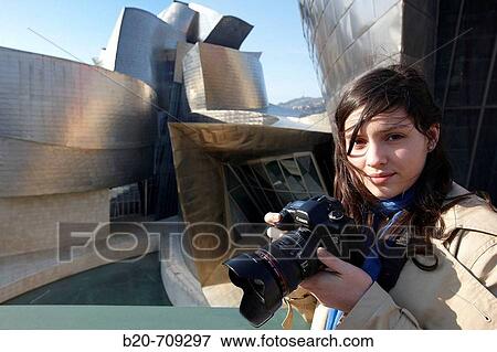 Young woman with camera in front of the Guggenheim Museum, Bilbao. Biscay, Euskadi, Spain View Large Photo Image Stock Photo - Young woman with camera in front of the Guggenheim Museum, Bilbao. Biscay, Euskadi, Spain. Fotosearch