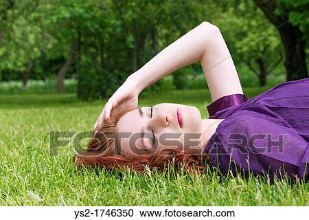 Young woman with closed eyes lying on the grass in a park View Large Photo Image Stock Image - Young woman with closed eyes lying on the grass in a park. Fotosearch