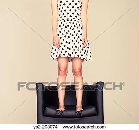 Young woman with cool attitude standing on leather armchair with bare feet. 1015 View Large Photo Image Stock Image - Young woman with cool attitude standing on leather armchair with bare feet. 1015. Fotosearch
