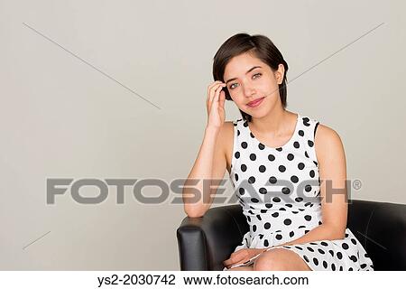 Young woman with dotted dress sitting in leather armchair. 1015 View Large Photo Image Stock Image - Young woman with dotted dress sitting in leather armchair. 1015. Fotosearch