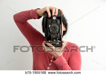 Stock Photo - Young woman with face covered with a old photographic camera. Fotosearch