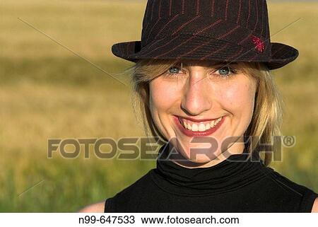 Young woman with hat, blond standing outdoor, being all smiles, good mood, looking to the camera, summertime View Large Photo Image Stock Image - Young woman with hat, blond standing outdoor, being all smiles, good mood, looking to the camera, summertime. Fotosearch