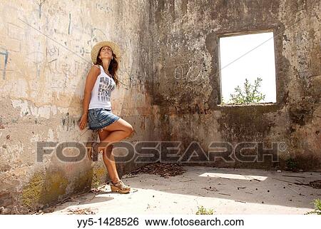 Young woman with hat, leaning on an old wall View Large Photo Image Stock Photograph - Young woman with hat, leaning on an old wall. Fotosearch