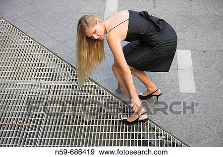 Young woman with her high heeled shoe stuck in a pavement drain cover View Large Photo Image Stock Photo - Young woman with her high heeled shoe stuck in a pavement drain cover. Fotosearch